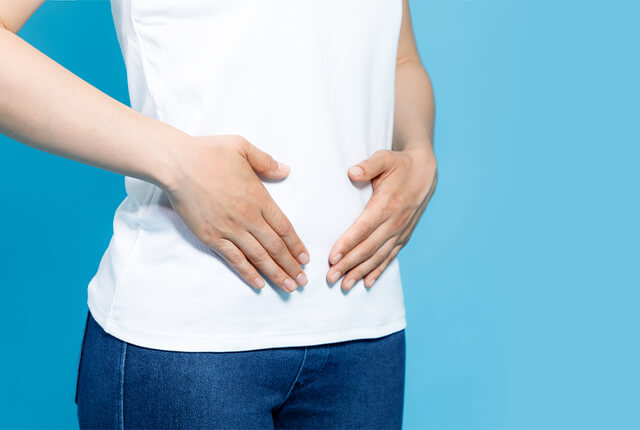 腹部を押さえている女性